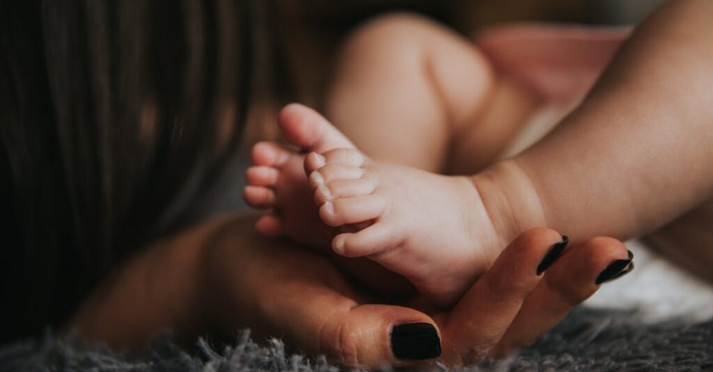 Close-up of a mother's hand gently holding her baby's tiny feet, symbolizing warmth and affection.